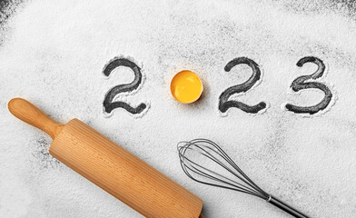 The inscription 2023 on flour on a kitchen board for working with dough.