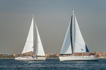 Sailboats with unrecognizable people crossing courses against the city