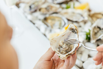 A man's hands squeezes fresh lemon juice onto an raw opened oyster, lifestyle food, ready to eat....