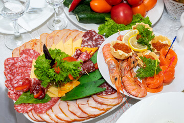 Delicious cold snacks are ready to eat. Cut meat and seafood on the festive table.