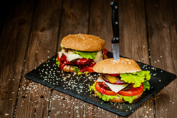 Top view of delicious burgers with beef, cheese, tomato, lettuce on stone board. Selective focus