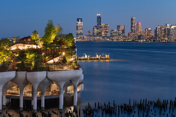 New York City, Little Island public park in evening with view of Downtown Jersey City. Elevated park at Hudson River Park (Pier 55), West Village, Manhattan