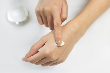 Woman applying cream on clean hand skin for beauty and spa treatment skin care on white color background.