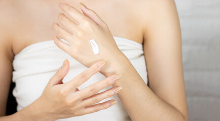 Beauty and spa treatment concept. Asian woman applying cream on hand.