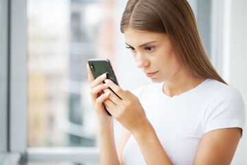Fototapeta na wymiar Attractive woman looking at smartphone screen, reading media news