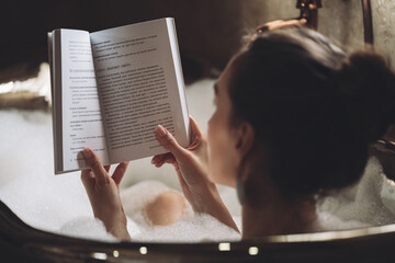 beautiful sexy girl in a bubble bath reading a book.