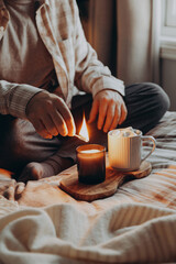 a caucasian man relaxing at home, lighting candle, drinking coffee in bed
