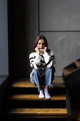 Cute young woman sits on wooden stairs.