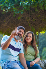 Fototapeta premium Young indian couple pointing and watching on opposite site at garden