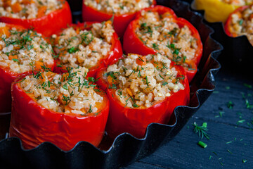 Stuffed pepper. Stewed pepper
 with rice and minced meat. Baked peppers in a cast iron pan on a black background. Healthy Romanian food.
