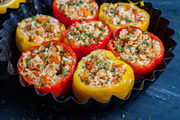 Stuffed pepper. Stewed pepper
 with rice and minced meat. Baked peppers in a cast iron pan on a black background. Healthy Romanian food.
