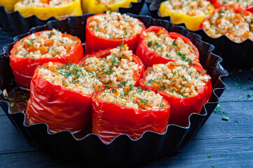 Stuffed pepper. Stewed pepper
 with rice and minced meat. Baked peppers in a cast iron pan on a black background. Healthy Romanian food.
