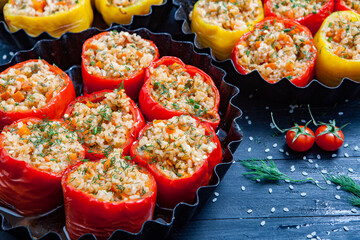 Stuffed pepper. Stewed pepper
 with rice and minced meat. Baked peppers in a cast iron pan on a black background. Healthy Romanian food.
