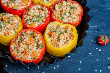 Stuffed pepper. Stewed pepper
 with rice and minced meat. Baked peppers in a cast iron pan on a black background. Healthy Romanian food.
