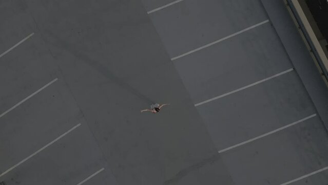 Drone pull away of a girl dancing alone on a rooft top parkade