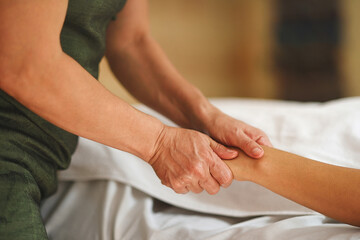 Fototapeta na wymiar Hands of masseur pressing hands of patient in close up shot with warm tones
