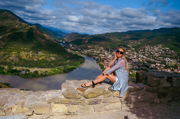 Young woman tourist posing on observation deck on windy weather, confluence of two rivers Aragvi...