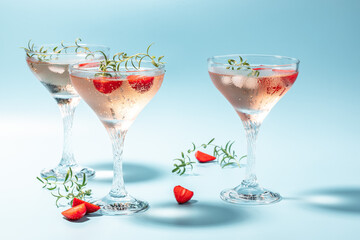 refreshing fruit cocktail. Glasses with cold pink champagne or punch with wine strawberries on blue background. place for text