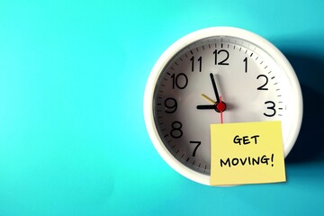 Wall clock on blue copy space background with handwritten note GET MOVING!, concept of having difficulty setting aside exercise time, reminder for health improvement by being more physically active