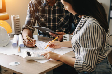 Two colleagues discussing data working and tablet, laptop with on on architectural project at construction site at desk in office.