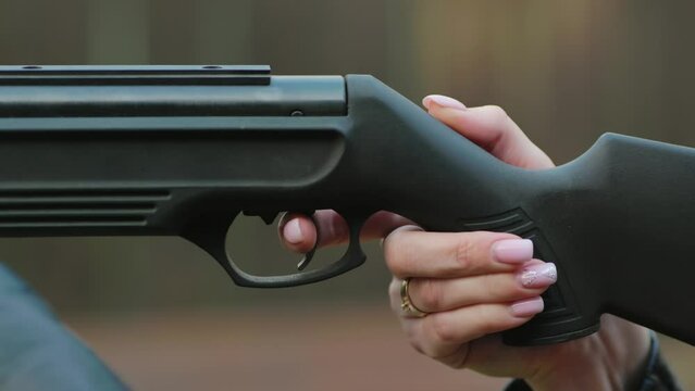 The girl is shooting from an air gun. Close-up of her hands.