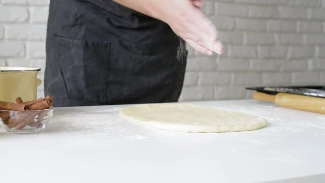 Male chef working with dough, cooking cinnamon rolls
