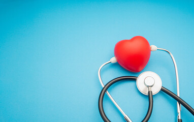 Top view of a stethoscope and a red heart shape on a blue background