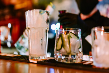 hands of a bartender with black gloves making cocktail on a bar counter.