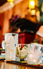 hands of a bartender with black gloves making cocktail on a bar counter.