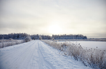 Winter landscape with snowy road and forest covered with hoar frost, selective focus