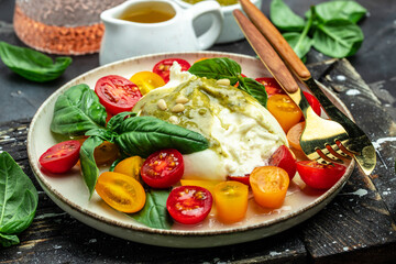Salad burrata cheese tomatoes and green pesto. Delicious balanced food concept. superfood concept. Healthy, clean eating. Vegan or gluten free diet. top view