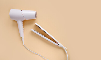 Top view of hair straightener and hair dryer on beige background. Hair care concept. light hair...