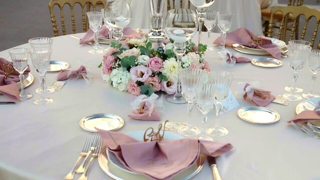 Gorgeous round banquet tables decorated with expensive silverware, personalised fabric napkins, crystal goblets, candles and charming fresh flowers bouquets. Prepared banquet table for wedding
