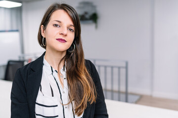 Portrait of serious young brunette executive girl in American jacket sitting at office desk. Entrepreneur woman.entrepreneur