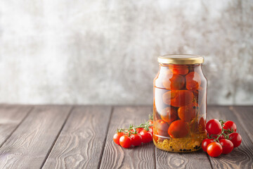 Pickled red cherry tomatoes in a glass jar Food preserving for autumn or winter time. Copy space
