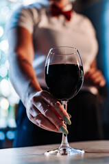 waiter hold red wine into a glass in cafe or bar