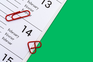 Herzförmige rote Büroklammer mit weiterer Büroklammern auf Kalender mit grünem Hintergrund