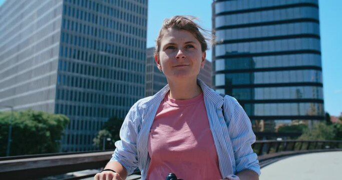 Portrait of authentic cool young woman use electric rental scooter in city on sunny summer day. Shared economy concept, urban mobility in big city, last kilometer transportation