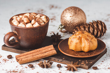Hot chocolate drink with marshmallows in a cup and sweet bakery eclair dessert sprinkled with cocoa...