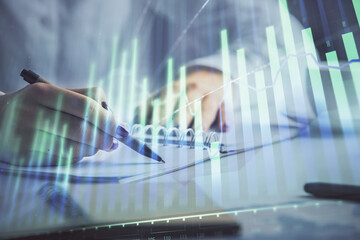 Double exposure of woman's hands making notes with forex graph hologram. Concept technical analysis.