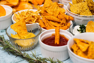 Spicy tortilla chips and sauces in the bowl, on the wooden table