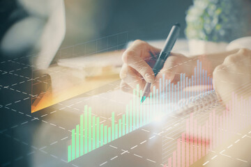 Financial forex graph displayed on hands taking notes background. Concept of research. Multi exposure