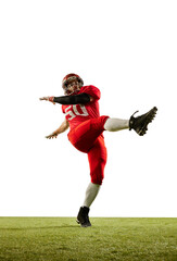 Obraz na płótnie Canvas Kick the ball. Professional american football player in sports uniform and protective helmet training with ball isolated over white background. Sport, team, competition, championship