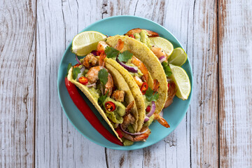 Mexican tacos with shrimp,guacamole and vegetables on wooden table. Top view