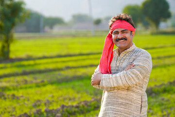 Happy Indian farmer standing at agriculture field. - obrazy, fototapety, plakaty