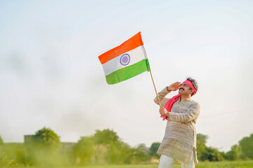 indian farmer saluting to national flag at agriculture field.