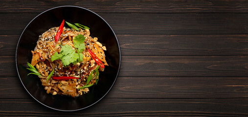 Noodles with chicken and vegetables, on a black plate