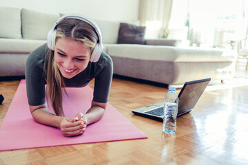 Caucasian young woman training at home watching an online class on her laptop computer - healthy lifestyle concepts.