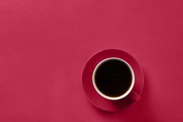 Cup of black coffee on viva magenta background. Trendy color of 2023 - Viva Magenta. View from above.