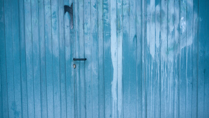 Puerta de metal corrugado azul manchada y deteriorada